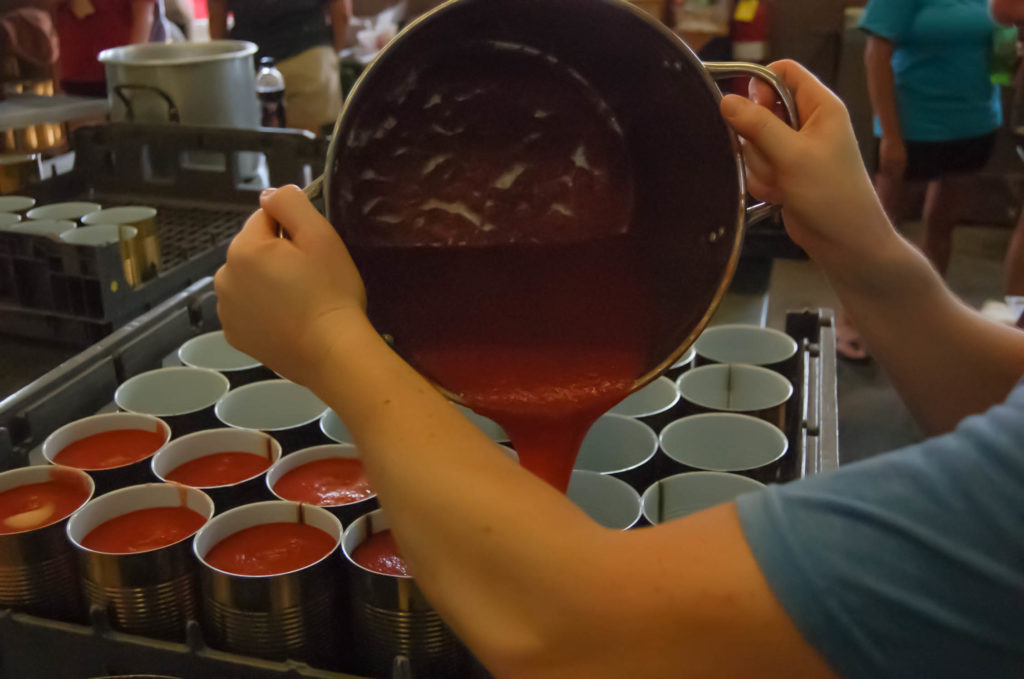 Pouring tomato sauce into the cans. 